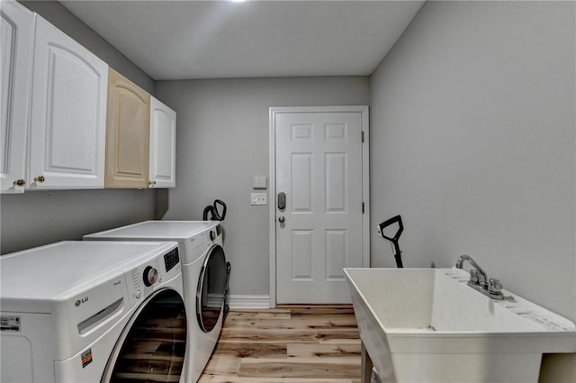 washroom with baseboards, separate washer and dryer, a sink, light wood-style floors, and cabinet space