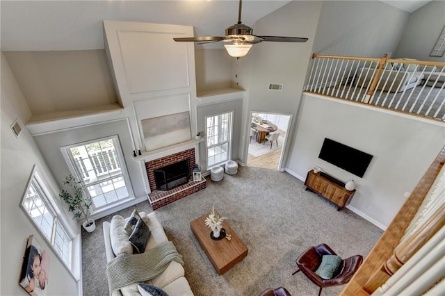 living room featuring a high ceiling, a brick fireplace, visible vents, ceiling fan, and carpet