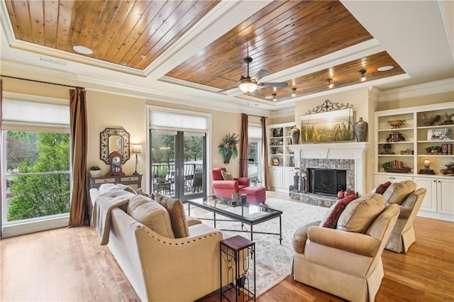 living room featuring a raised ceiling, plenty of natural light, a fireplace, and wood ceiling