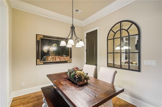 dining room with visible vents, baseboards, crown molding, and wood finished floors