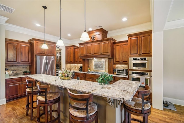 kitchen with backsplash, crown molding, visible vents, stainless steel appliances, and wood finished floors