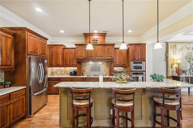 kitchen featuring decorative light fixtures, a kitchen island with sink, decorative backsplash, light wood finished floors, and appliances with stainless steel finishes