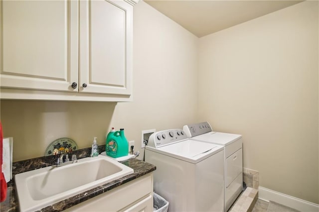 clothes washing area with baseboards, washing machine and clothes dryer, a sink, and cabinet space