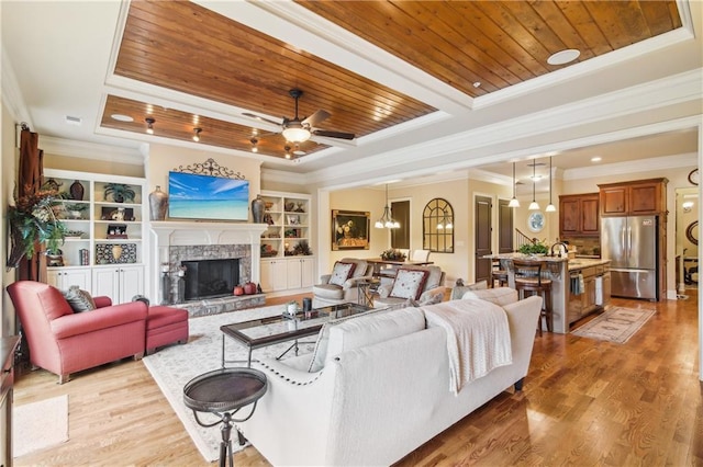 living room with light wood-type flooring, wooden ceiling, a tray ceiling, and ornamental molding