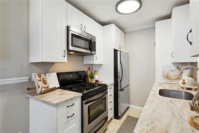 kitchen featuring light stone counters, white cabinets, sink, appliances with stainless steel finishes, and crown molding