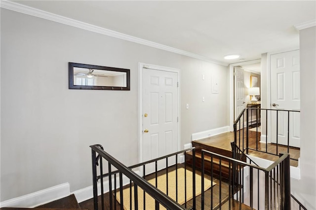 stairs with wood-type flooring, crown molding, and ceiling fan