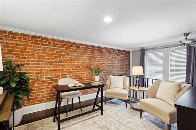 living area featuring brick wall, light hardwood / wood-style flooring, ornamental molding, and ceiling fan