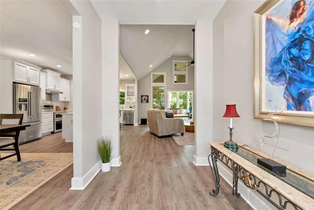 foyer entrance featuring ceiling fan, high vaulted ceiling, and light hardwood / wood-style floors