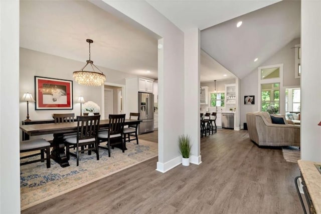 dining area with an inviting chandelier, lofted ceiling, and wood-type flooring