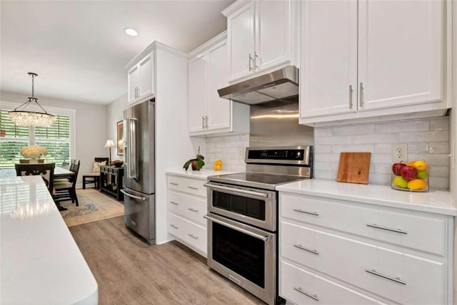 kitchen featuring hanging light fixtures, light wood-type flooring, stainless steel appliances, decorative backsplash, and white cabinets