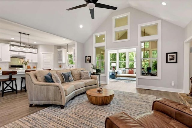 living room featuring ceiling fan, sink, high vaulted ceiling, and light wood-type flooring