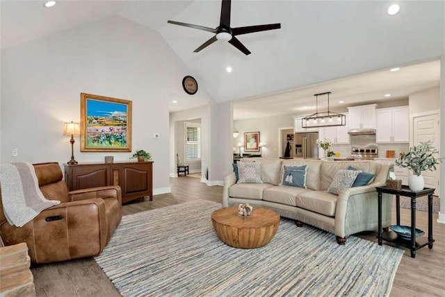 living room with ceiling fan, high vaulted ceiling, and light hardwood / wood-style floors