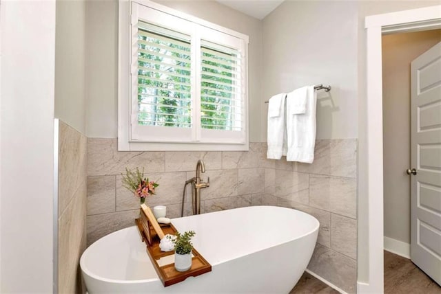 bathroom with a washtub and tile walls