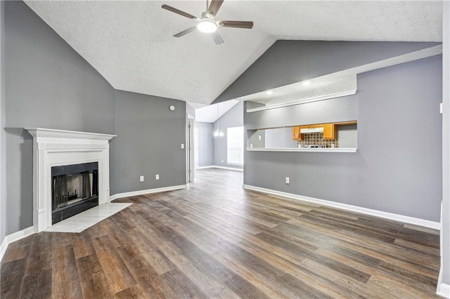 unfurnished living room featuring a fireplace with flush hearth, lofted ceiling, wood finished floors, and a ceiling fan