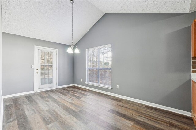 unfurnished dining area with lofted ceiling, a textured ceiling, dark wood-style floors, an inviting chandelier, and baseboards