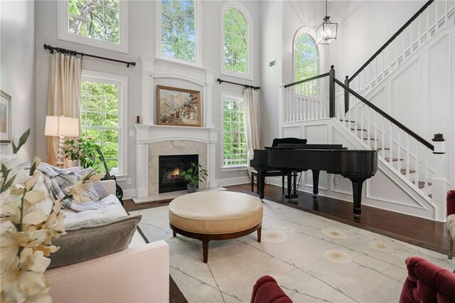 living area with visible vents, a towering ceiling, stairway, a high end fireplace, and a chandelier