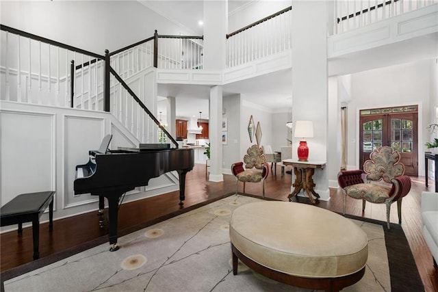 interior space featuring french doors, stairs, wood finished floors, a towering ceiling, and ornamental molding