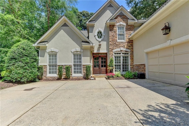 view of front of home featuring stucco siding, stone siding, and concrete driveway