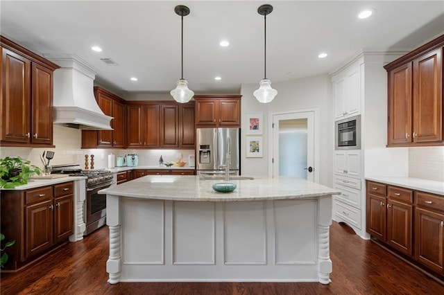 kitchen with decorative backsplash, an island with sink, premium range hood, stainless steel appliances, and dark wood-type flooring