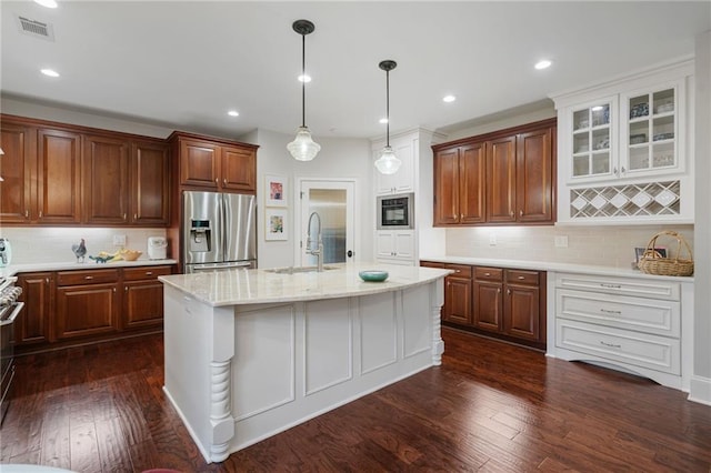 kitchen featuring visible vents, black microwave, stainless steel fridge with ice dispenser, a sink, and backsplash