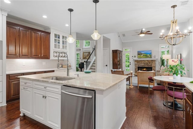 kitchen with a stone fireplace, a sink, dishwasher, and a healthy amount of sunlight