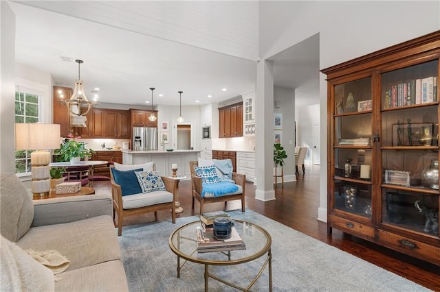 living room featuring recessed lighting, baseboards, dark wood-style floors, and a notable chandelier
