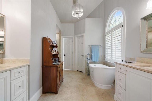 full bathroom with a freestanding bath, tile patterned flooring, a chandelier, two vanities, and vaulted ceiling