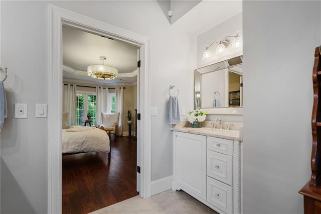 ensuite bathroom with crown molding, vanity, baseboards, wood finished floors, and ensuite bathroom