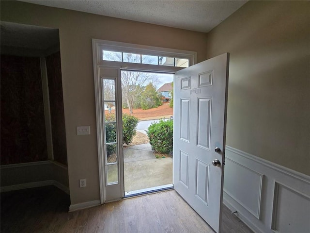 doorway to outside with a textured ceiling and light wood-type flooring