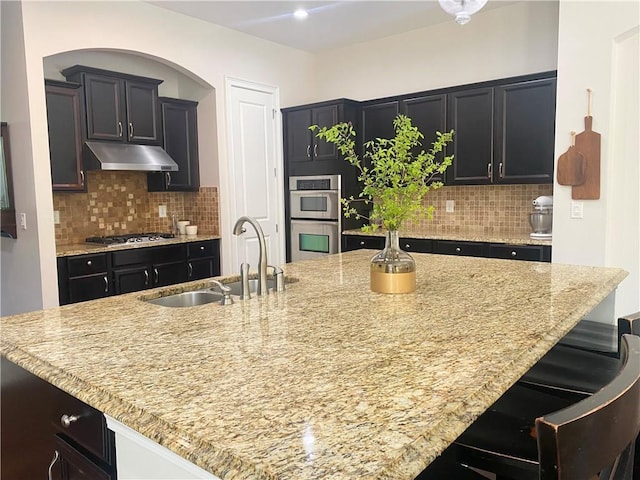 kitchen featuring a kitchen island with sink, sink, a kitchen breakfast bar, and appliances with stainless steel finishes