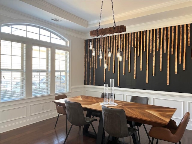 dining area with dark hardwood / wood-style floors, ornamental molding, and a tray ceiling