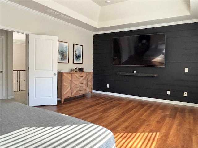 bedroom with dark wood-type flooring, crown molding, and a raised ceiling