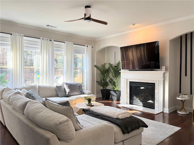 living room with crown molding, dark wood-type flooring, and ceiling fan