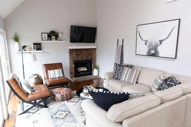 living room with hardwood / wood-style flooring, lofted ceiling, and a fireplace