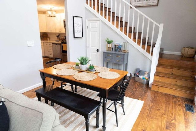 dining area with hardwood / wood-style floors and an inviting chandelier