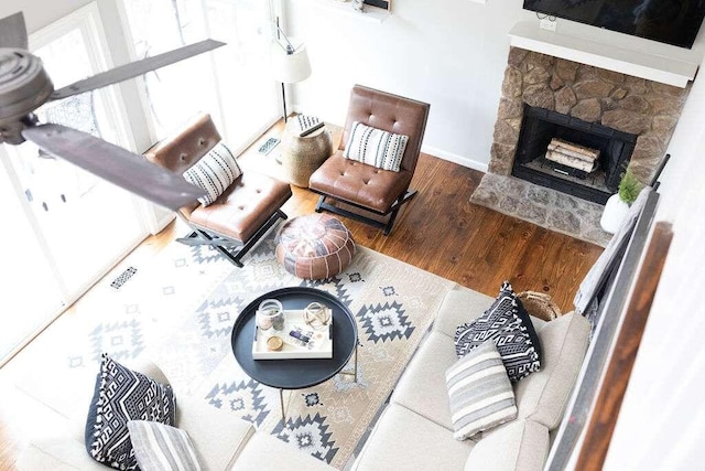 living room with a stone fireplace and hardwood / wood-style flooring