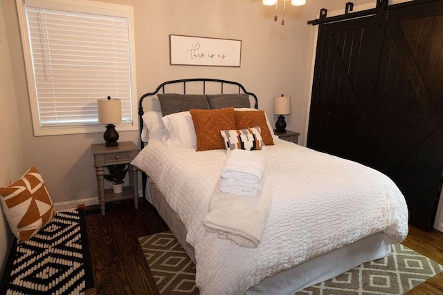 bedroom featuring a barn door and dark hardwood / wood-style flooring