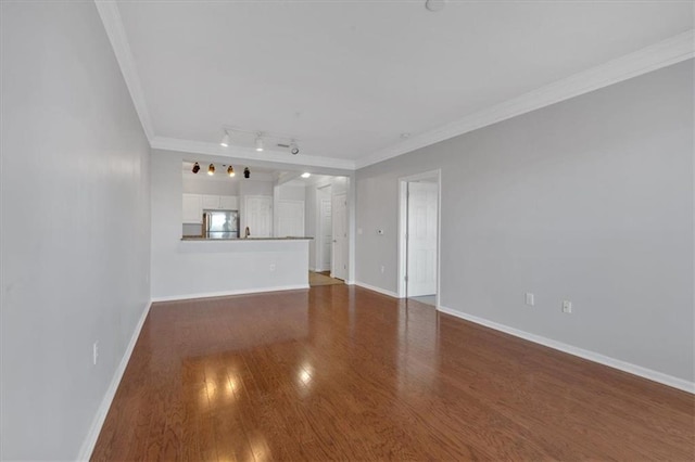 unfurnished living room featuring dark hardwood / wood-style flooring, rail lighting, and ornamental molding