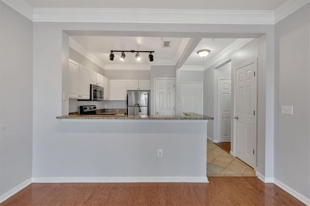 kitchen with appliances with stainless steel finishes, light stone countertops, white cabinets, light hardwood / wood-style floors, and kitchen peninsula