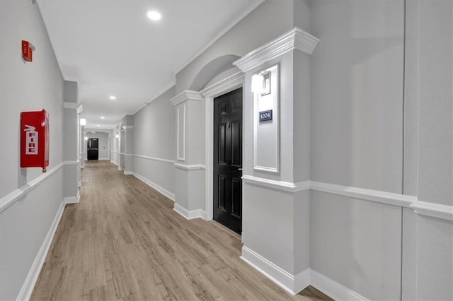 hallway with light wood-type flooring and decorative columns