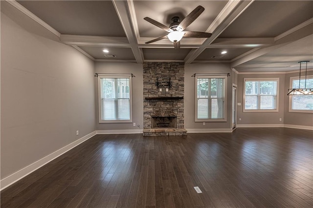 unfurnished living room featuring dark wood-type flooring, coffered ceiling, a stone fireplace, ornamental molding, and beamed ceiling