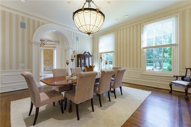 dining room with crown molding, hardwood / wood-style flooring, a chandelier, and ornate columns