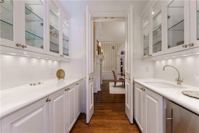 bar featuring dark wood-type flooring, sink, and white cabinets