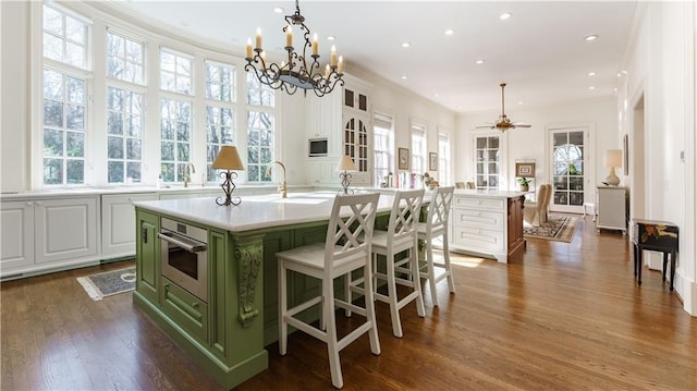 kitchen featuring an island with sink, hanging light fixtures, and white cabinets