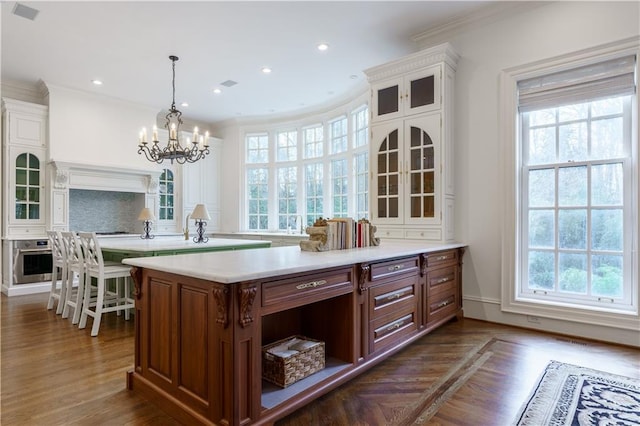 kitchen featuring stainless steel oven, decorative light fixtures, ornamental molding, dark hardwood / wood-style flooring, and backsplash