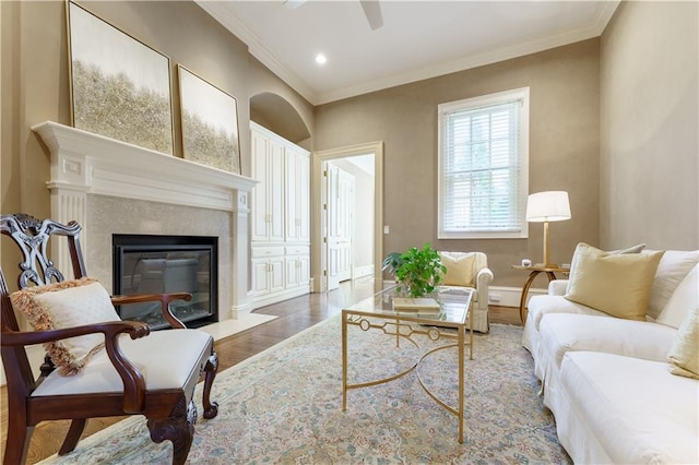 living room with hardwood / wood-style floors, a high end fireplace, ornamental molding, and ceiling fan