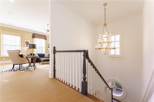 staircase with ornamental molding, a wealth of natural light, and a chandelier