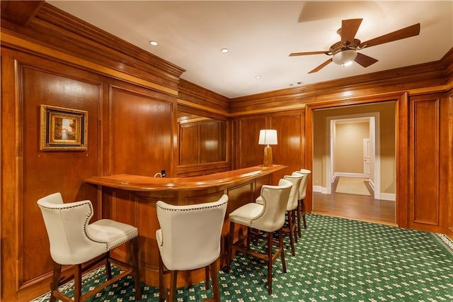 bar with ceiling fan and wood walls