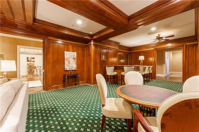 carpeted dining space featuring coffered ceiling, ornamental molding, wooden walls, beamed ceiling, and ceiling fan