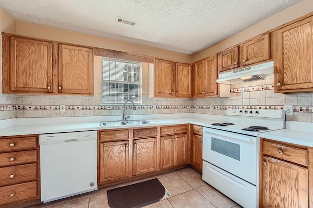 kitchen with decorative backsplash, visible vents, a sink, under cabinet range hood, and white appliances